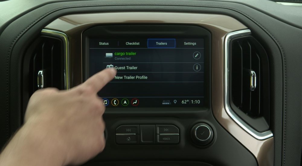 A person is shown selecting trailering options on the infotainment screen in a 2019 Chevy Silverado 1500.